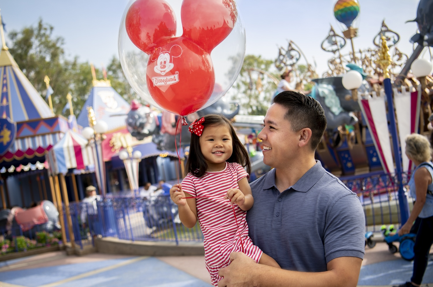 Father and daughter with a Mickey Mouse balloon at Disneyland® Park