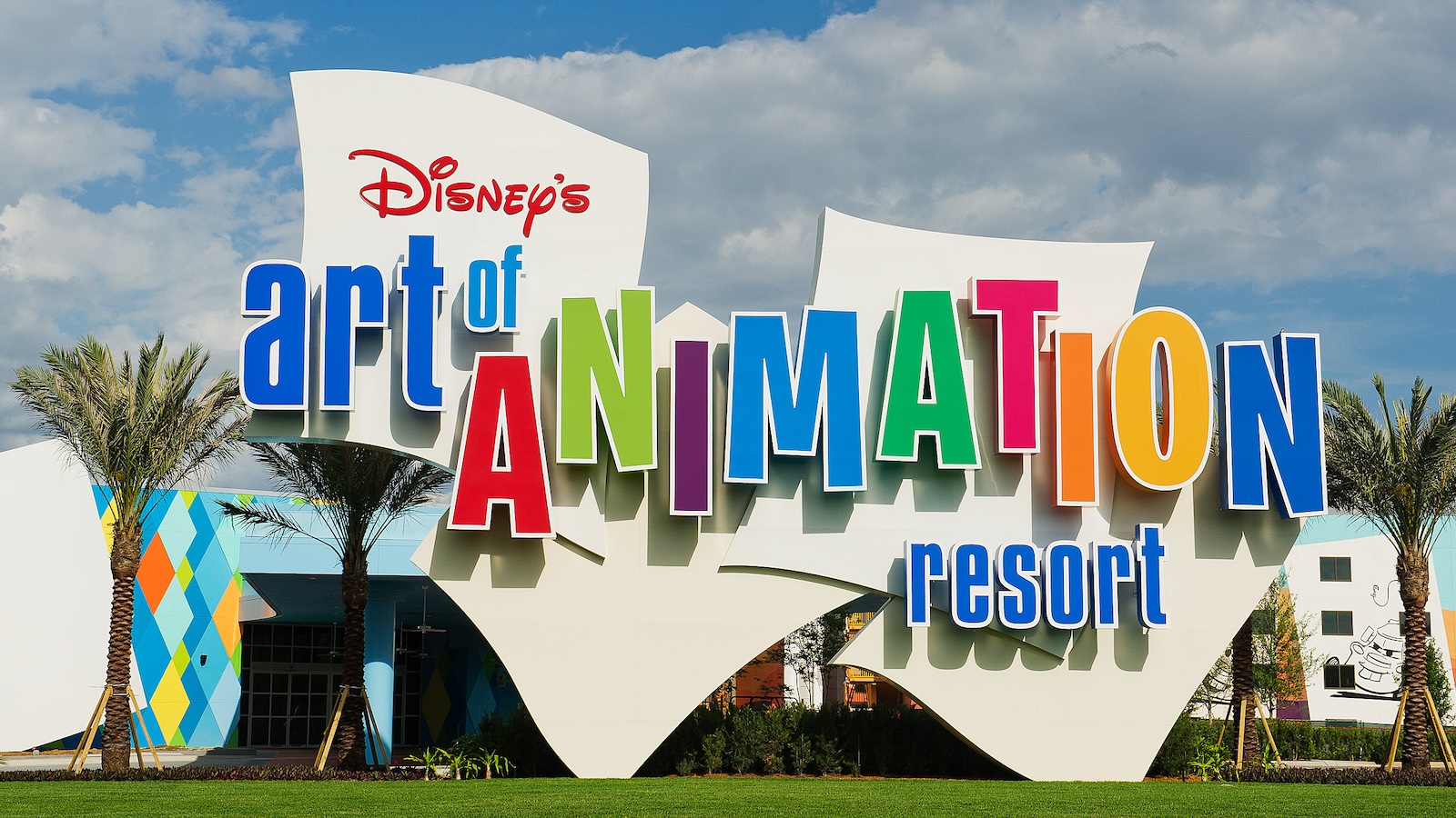 Entrance sign for Disney’s Art of Animation Resort featuring colorful letters, palm trees, and a blue sky.